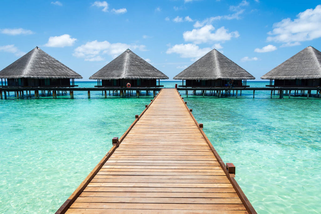 Overwater bungalows at the end of a wooden bridge.  