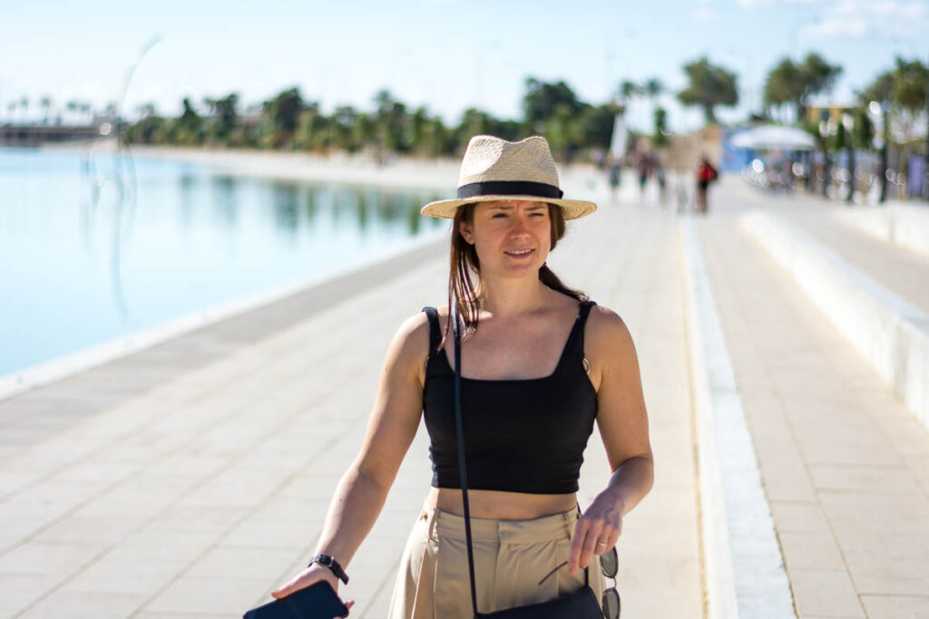 A woman in straw hat walking by the waterfrond in Palma. 