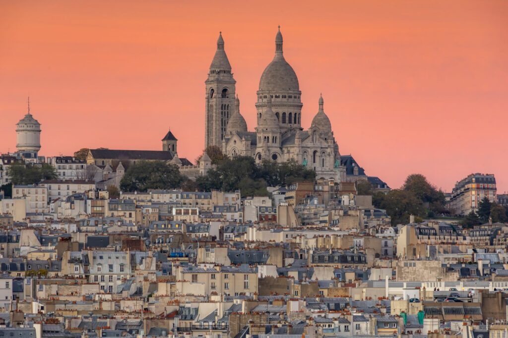 A stunning view of Sacre-Coeur Basilica in Paris with a vibrant orange sky at dusk.