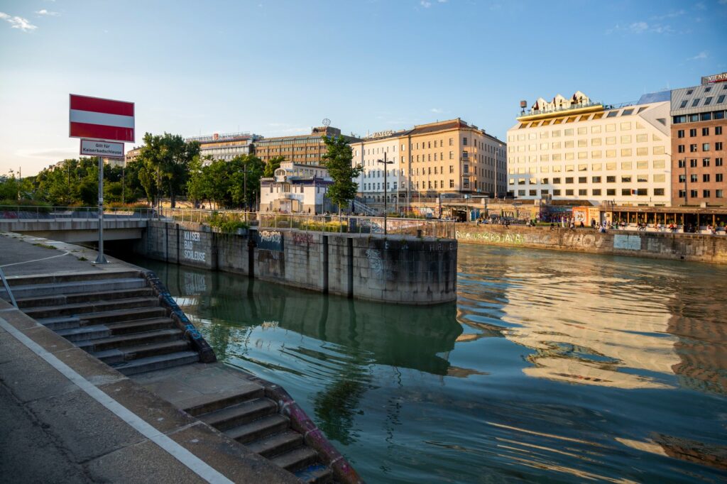 A scenic view of Vienna's urban canal at sunset with reflections and architecture.