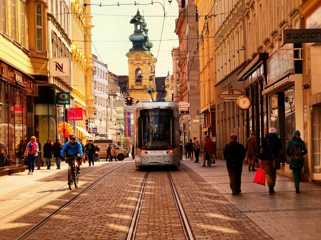 Urban street scene in Linz, Austria with tram, cyclists, and pedestrians.