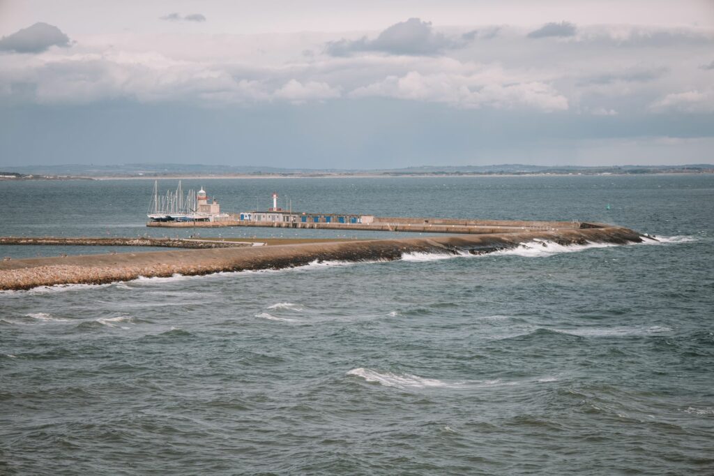 Scenic view of Dublin harbor with a lighthouse and boats, capturing a serene ocean landscape.