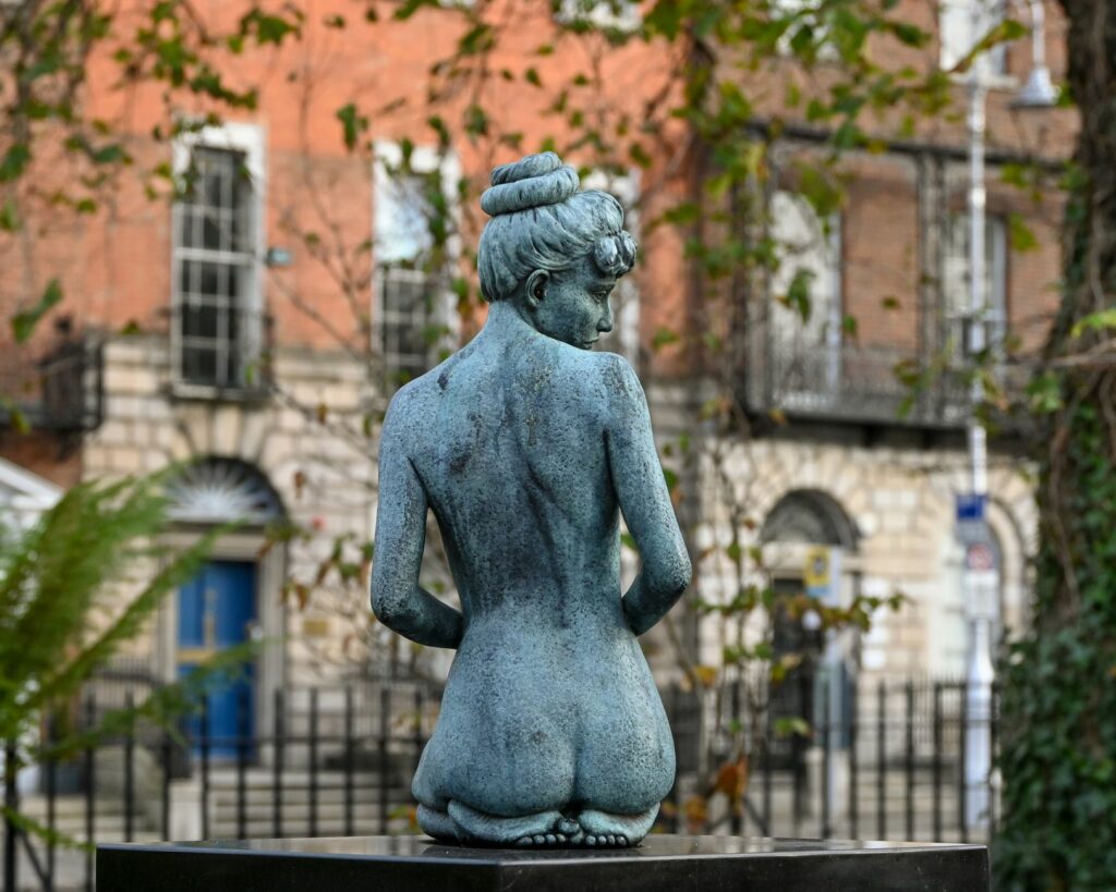 Bronze statue of a nude woman in a historic Dublin park, showcasing art and culture.