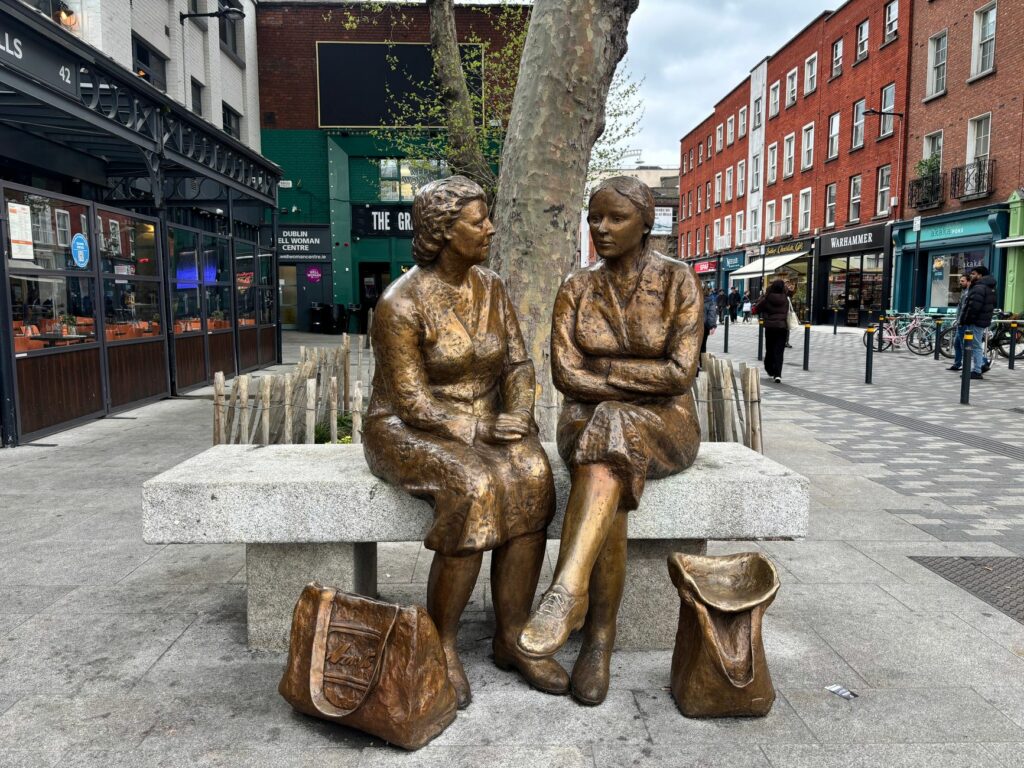Bronze sculptures of women on a Dublin street bench showcasing urban art.