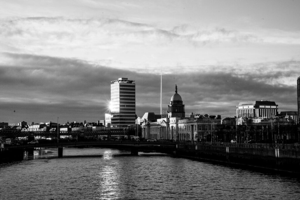 A stunning black and white cityscape of Dublin with a river view and dramatic clouds.
