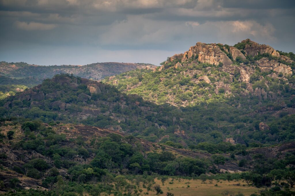 Aerial view of lush, rocky hills in Zimbabwe under a cloudy sky, showcasing natural beauty.