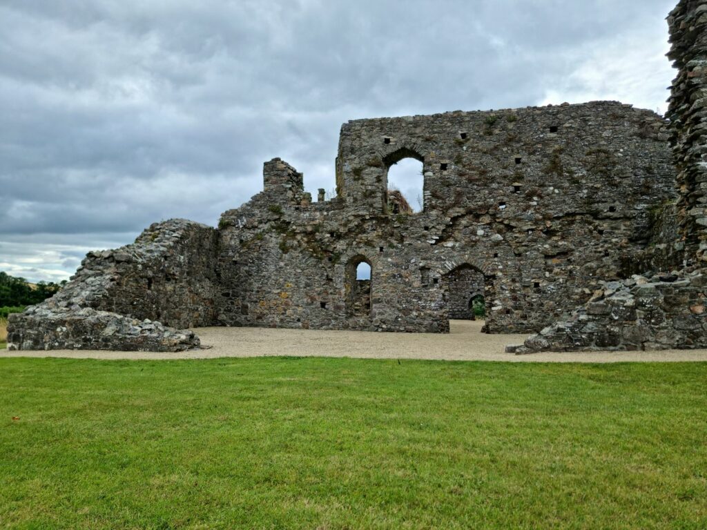 Explore the architectural charm of ancient stone ruins with large archways beneath a cloudy sky.