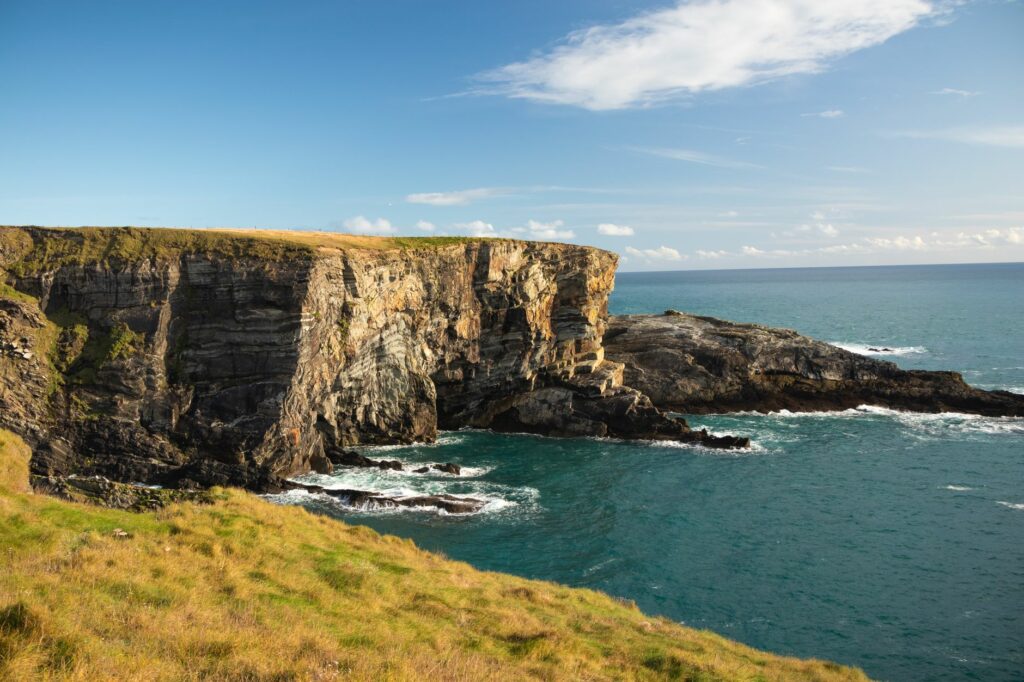 Gorgeous cliffside view overlooking the ocean in County Cork, Ireland, under a clear blue sky.