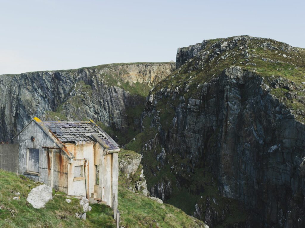 Rustic abandoned house perched on scenic cliffs in Cork, Ireland.