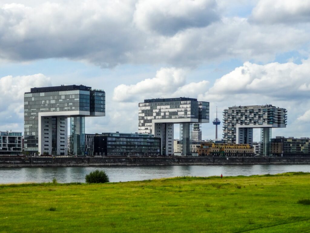 Modern Kranhaus buildings in Cologne, Germany, with lush green riverfront.