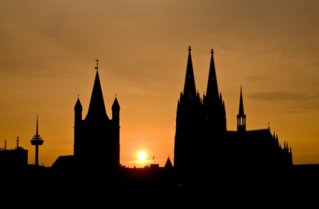 Majestic silhouette of Cologne Cathedral against a vibrant sunset sky.