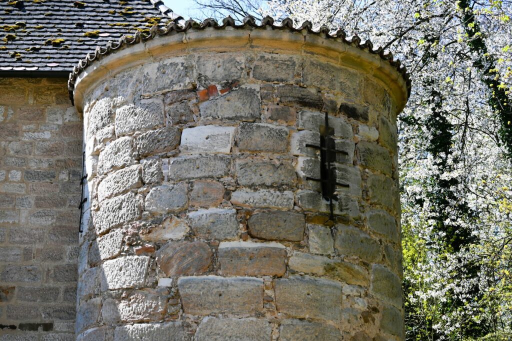 Close-up view of an ancient stone tower surrounded by blooming spring trees in Germany.