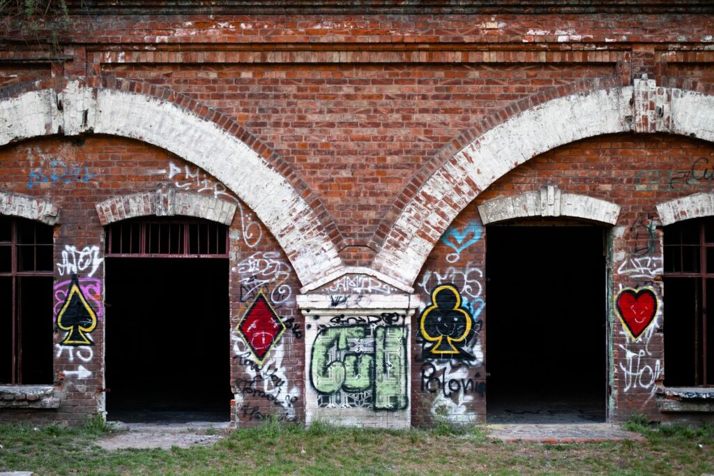 Red brick building with graffiti in Warsaw, Poland, showcasing urban art and architecture.