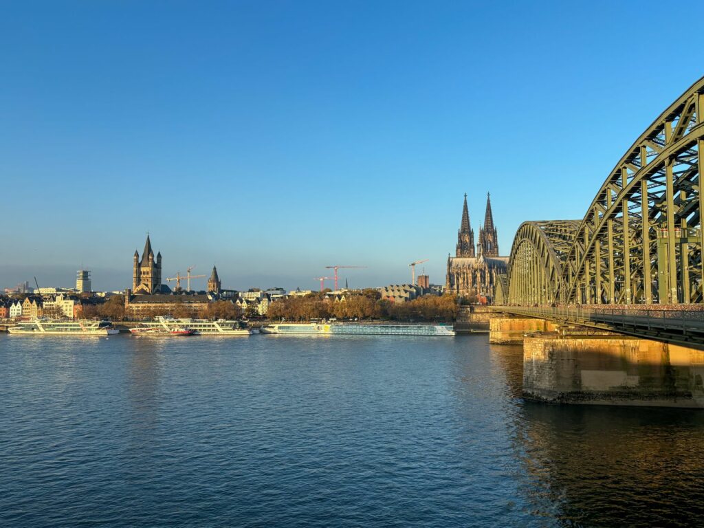 Scenic view of Cologne's iconic cathedral and Hohenzollern Bridge over the Rhine River.