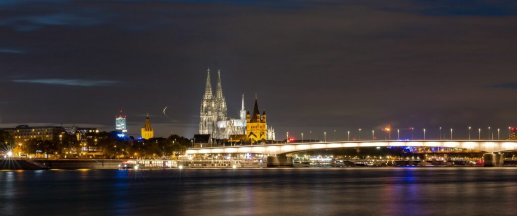 Beautiful night view of Cologne Cathedral and cityscape reflected over the Rhine River.