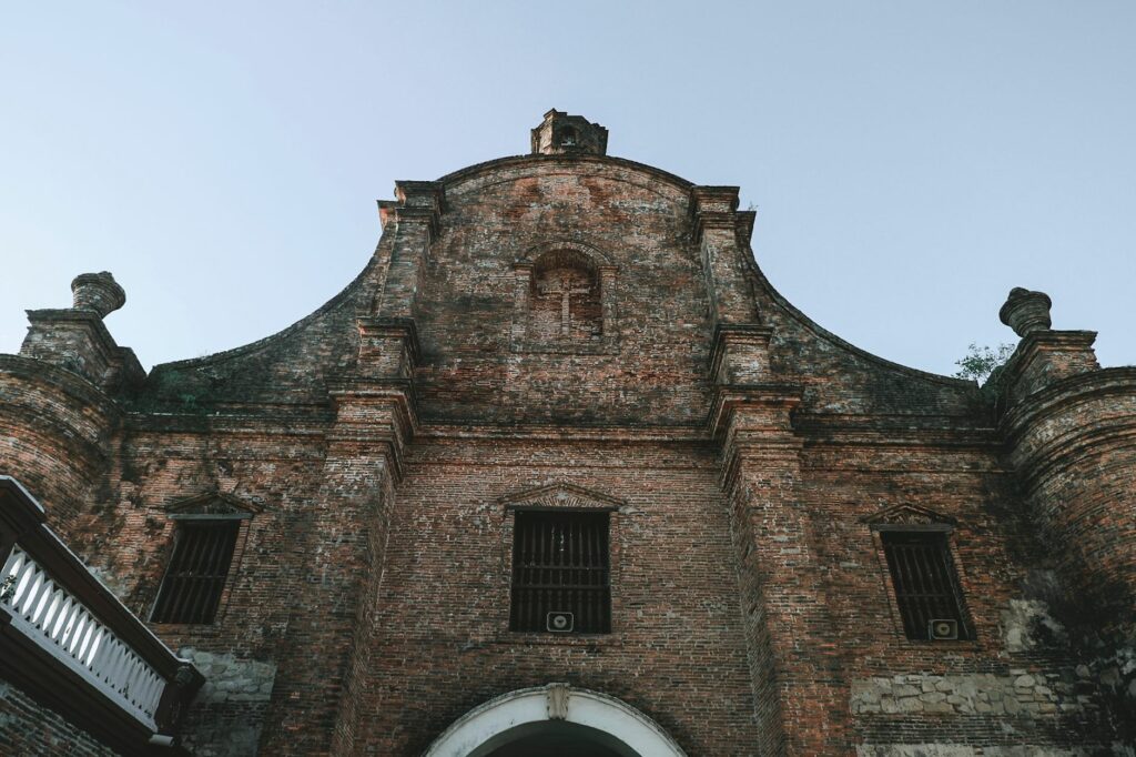 Low angle view of a historic brick church facade in Ilocos Sur, Philippines.