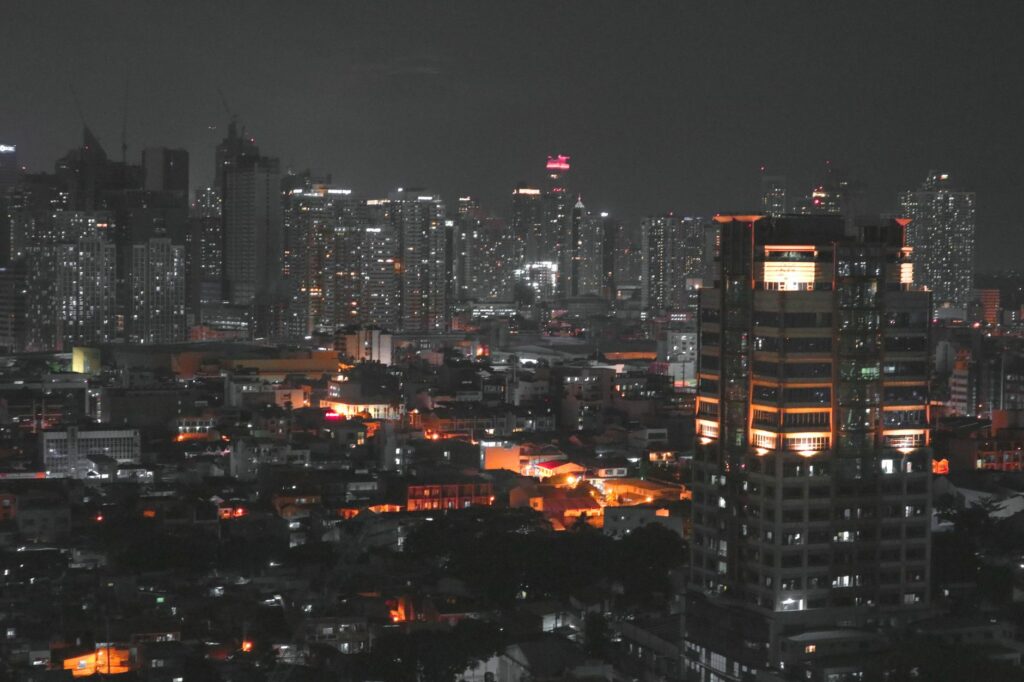 A stunning aerial view of Manila cityscape at night featuring brightly lit skyscrapers and urban glow.