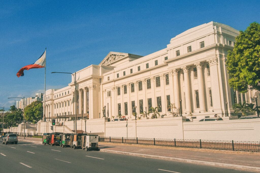 A sunny view of the National Museum of Fine Arts in Manila with the Philippine flag.