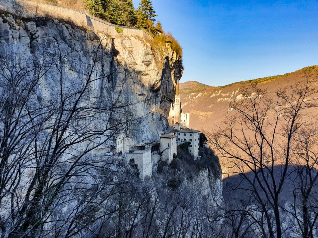 A breathtaking view of a sanctuary perched on a cliff in the Italian mountains during daylight.