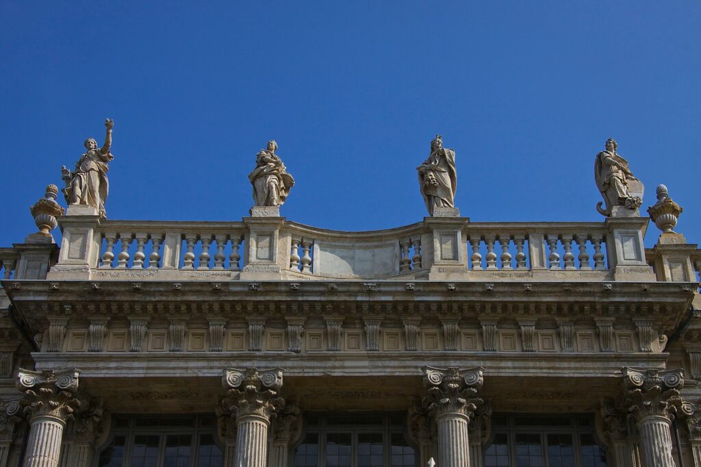 Elegant facade of Palazzo Madama in Torino featuring classical statues against a clear blue sky.