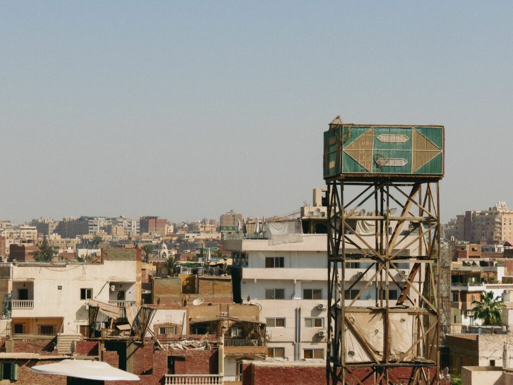 View of urban rooftops and water tower in Cairo cityscape.