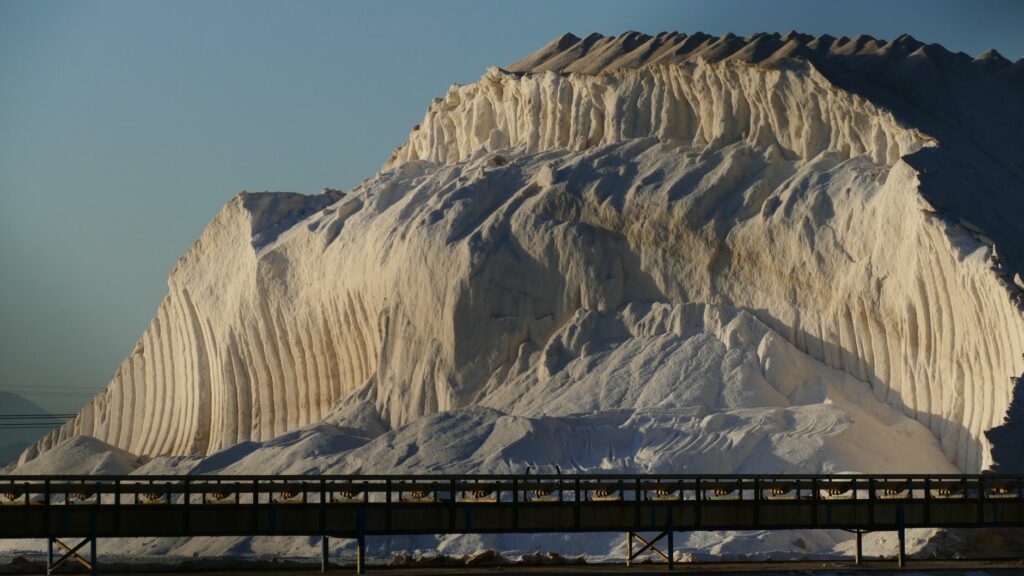 Breathtaking view of a large salt rock formation illuminated by sunlight in a rural outdoor setting.