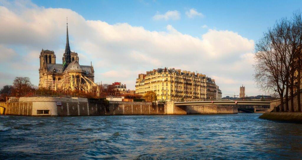 Scenic view of Notre Dame Cathedral by the Seine River in Paris during the day.