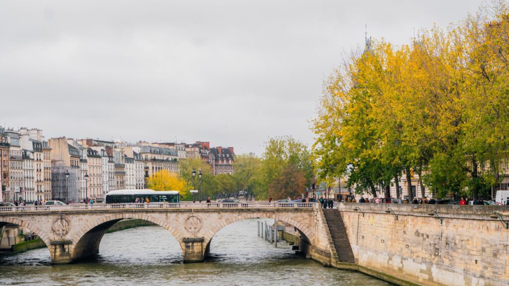 Charming autumnal view of a Parisian bridge and the Seine River with vibrant fall foliage.