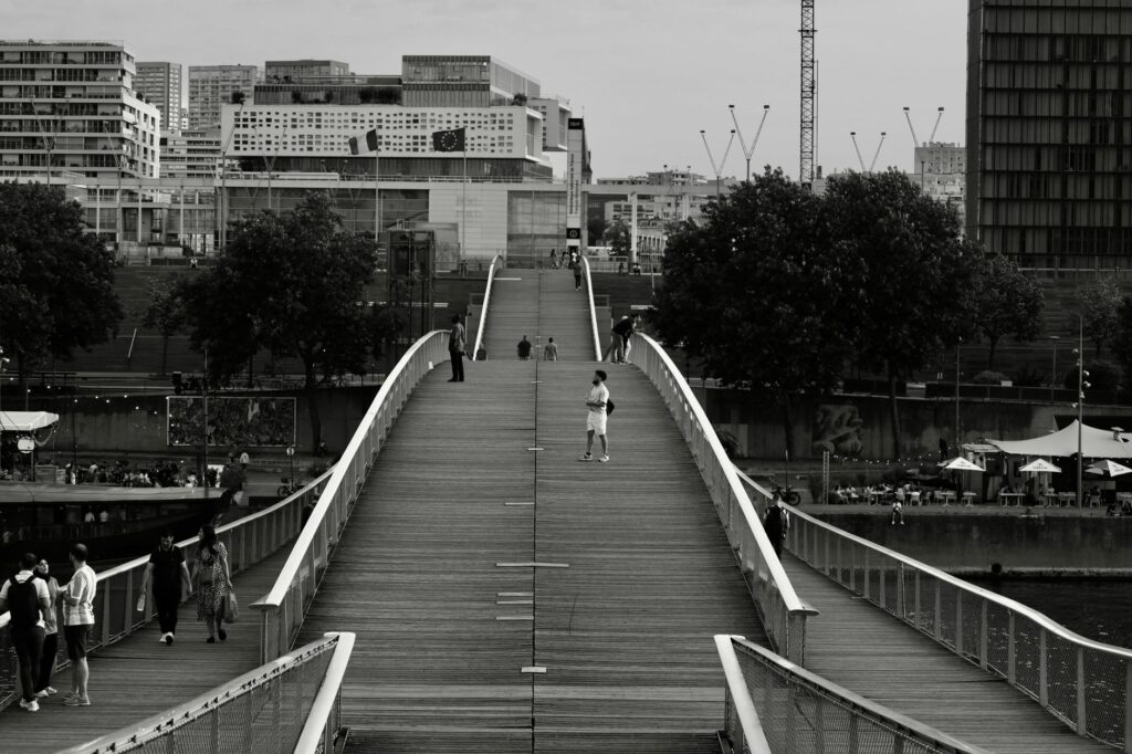 A monochrome view of a Parisian bridge bustling with people, capturing urban life.