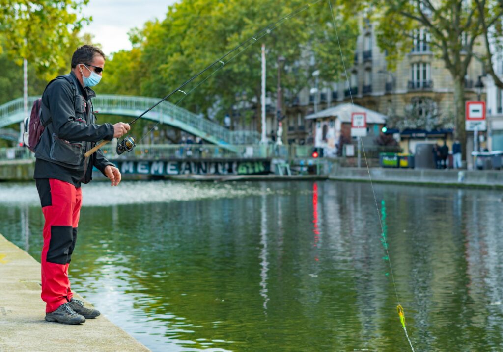 Man fishing with a rod on Canal Saint-Martin, Paris, showcasing urban leisure and scenic views.