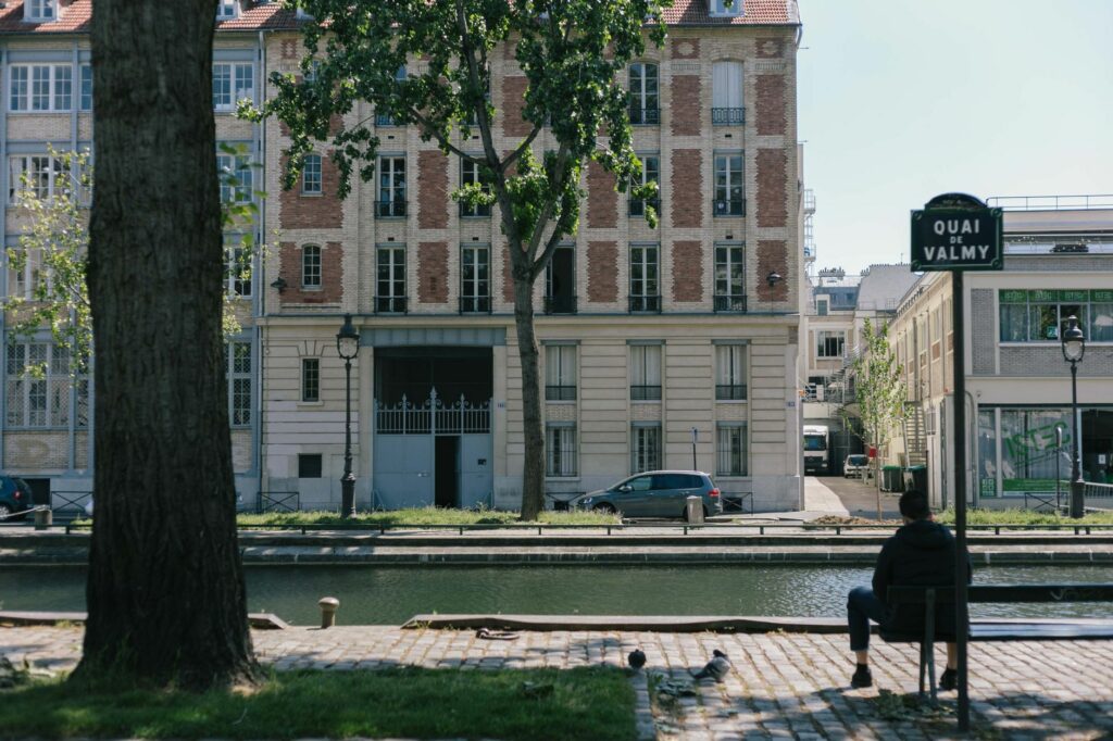 A serene view of Quai de Valmy in Paris with canal and classic architecture under clear skies.