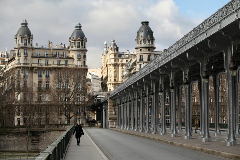 Elegant Haussmann architecture in Paris with a person walking along Pont de Bir-Hakeim.