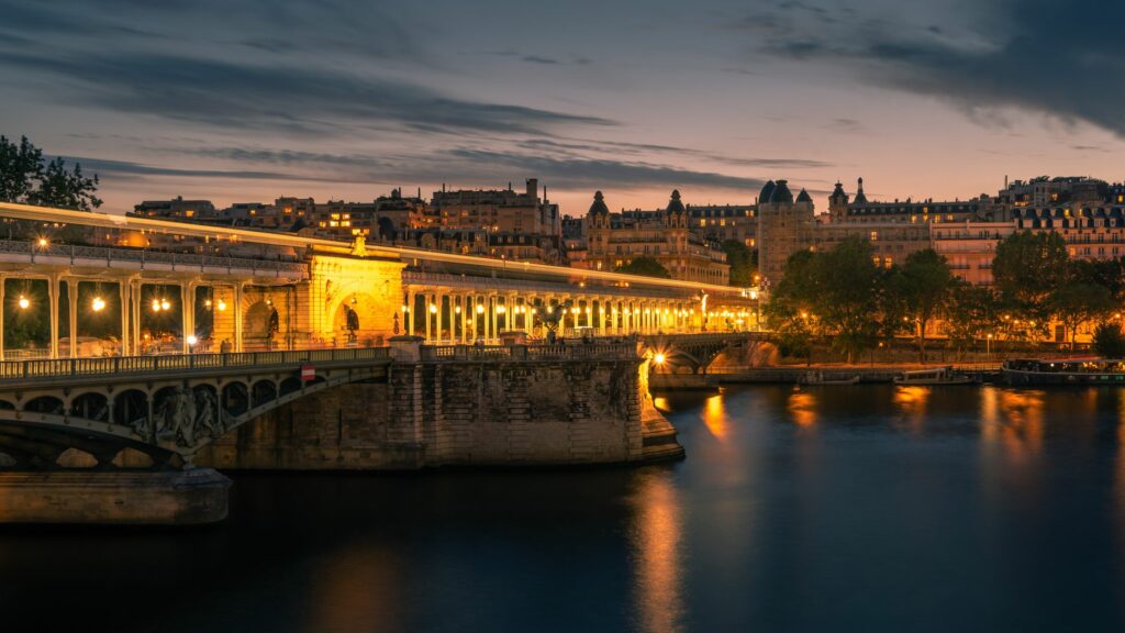 A stunning view of an illuminated bridge over the Seine River in Paris, capturing the city's night ambiance.